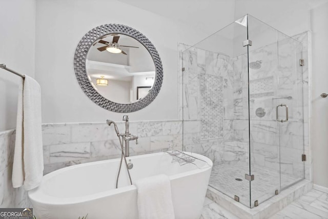 bathroom with ceiling fan, tile walls, marble finish floor, a soaking tub, and a shower stall