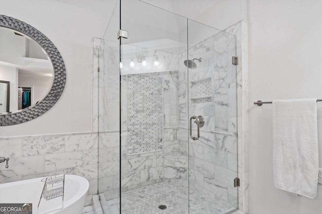 full bath with tile walls, a soaking tub, and a shower stall