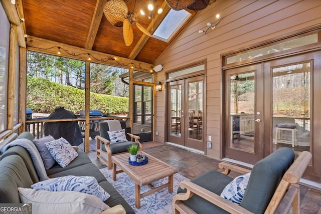 sunroom / solarium featuring french doors, lofted ceiling with skylight, wooden ceiling, and a ceiling fan