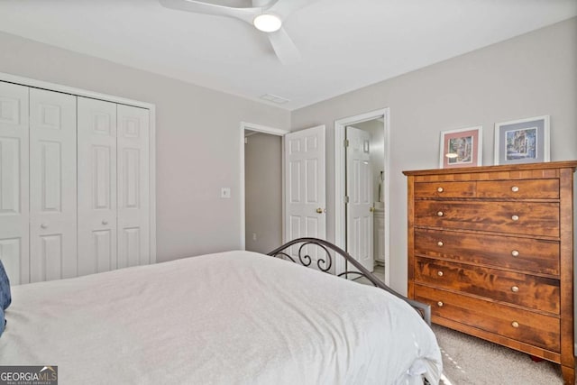 carpeted bedroom featuring a closet, ensuite bath, and a ceiling fan