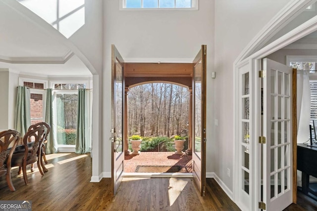 entrance foyer with arched walkways, french doors, baseboards, and wood finished floors