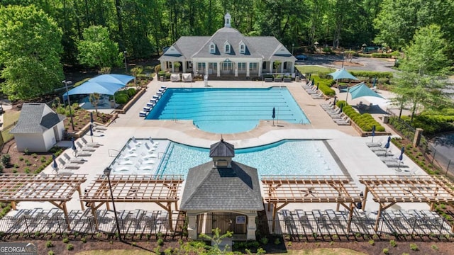 community pool with fence, an outbuilding, and a patio