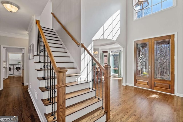 foyer entrance with arched walkways, french doors, ornamental molding, separate washer and dryer, and wood finished floors