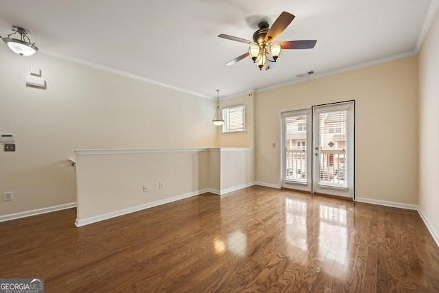 spare room featuring baseboards, visible vents, wood finished floors, and ornamental molding