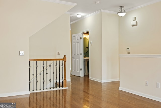 interior space featuring crown molding, baseboards, wood finished floors, and an upstairs landing