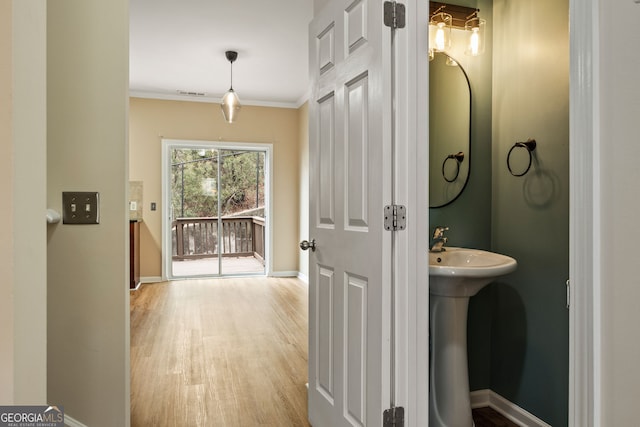 bathroom with baseboards, visible vents, ornamental molding, and wood finished floors