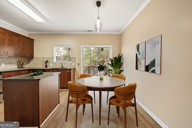 dining area featuring baseboards, light wood-style floors, visible vents, and crown molding