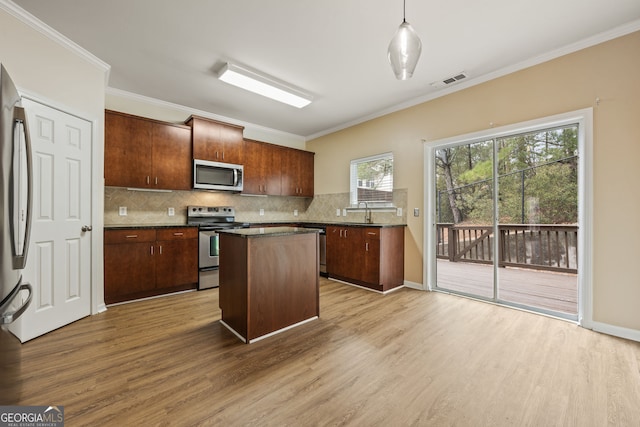 kitchen featuring stainless steel appliances, visible vents, a kitchen island, and wood finished floors