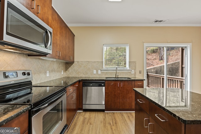 kitchen with light wood finished floors, backsplash, appliances with stainless steel finishes, ornamental molding, and a sink