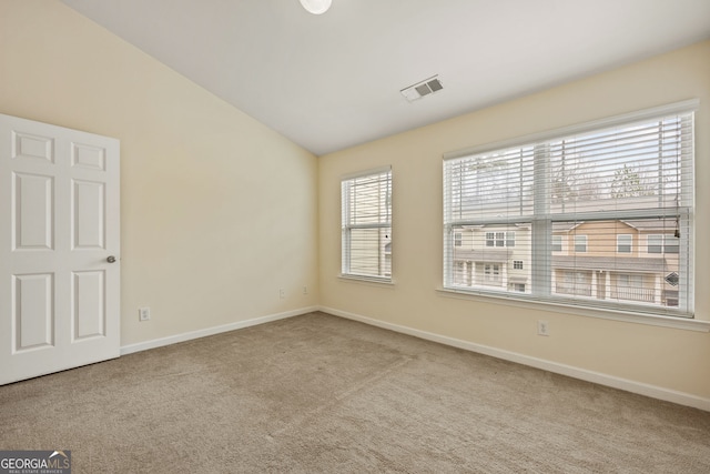 carpeted empty room with baseboards, visible vents, and vaulted ceiling