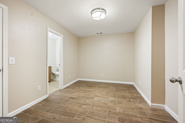 unfurnished room featuring wood tiled floor, visible vents, and baseboards