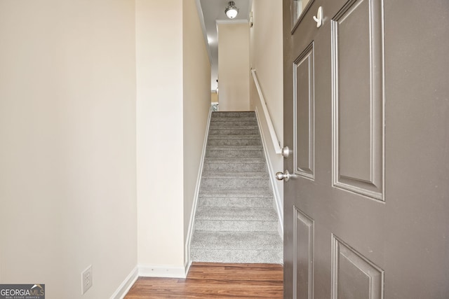 staircase featuring baseboards and wood finished floors