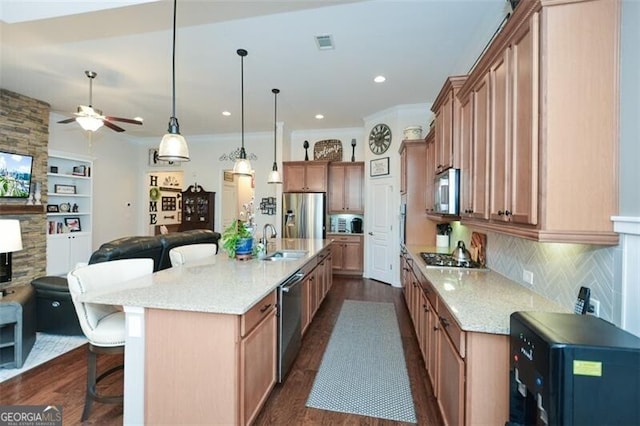 kitchen featuring visible vents, open floor plan, stainless steel appliances, a kitchen bar, and a sink