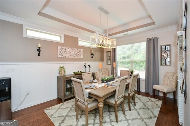 dining space with a tray ceiling, wainscoting, wood finished floors, and crown molding