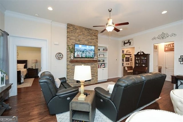 living area featuring built in shelves, a fireplace, wood finished floors, a ceiling fan, and ornamental molding