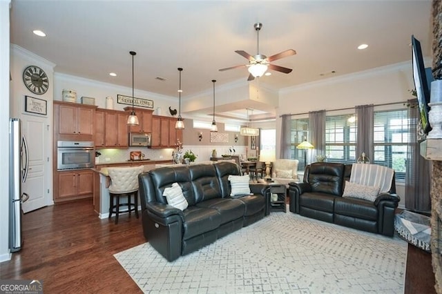 living area with ceiling fan, ornamental molding, dark wood finished floors, and recessed lighting