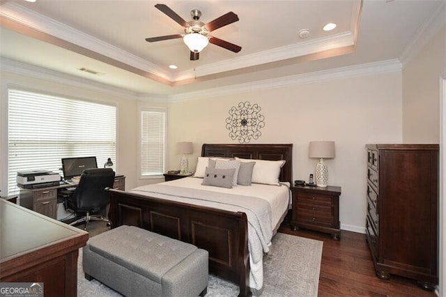 bedroom with baseboards, visible vents, dark wood finished floors, a tray ceiling, and crown molding