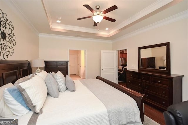 bedroom with ornamental molding, ceiling fan, a tray ceiling, and wood finished floors