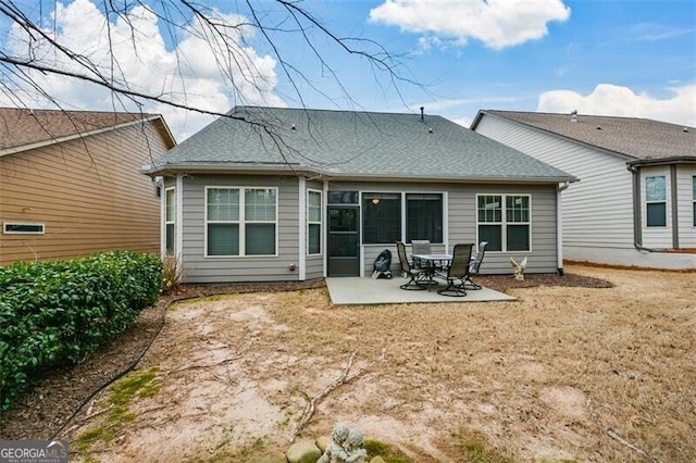 rear view of property with roof with shingles and a patio area