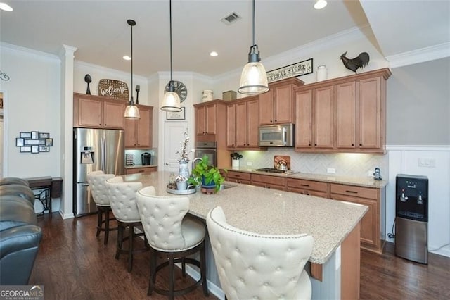 kitchen featuring visible vents, dark wood-style floors, a breakfast bar area, ornamental molding, and stainless steel appliances