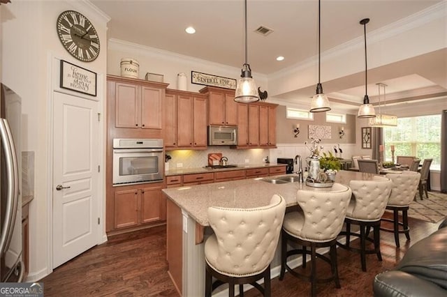 kitchen featuring dark wood-style floors, stainless steel appliances, visible vents, open floor plan, and a sink