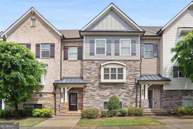 townhome / multi-family property with a standing seam roof, metal roof, board and batten siding, and stone siding