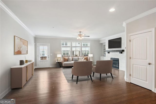 living area featuring crown molding, baseboards, hardwood / wood-style floors, a fireplace, and a ceiling fan