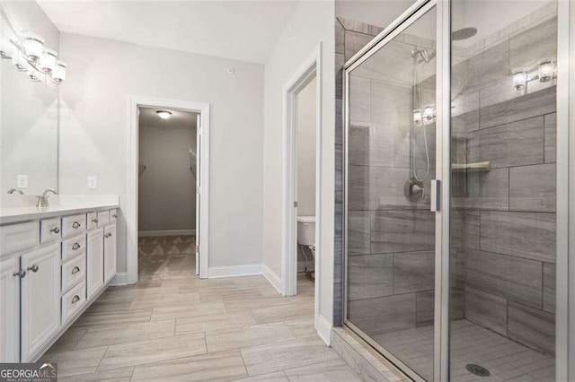 bathroom featuring baseboards, vanity, a shower stall, and toilet