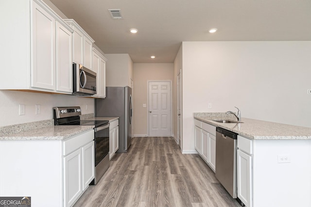 kitchen featuring visible vents, appliances with stainless steel finishes, light wood-type flooring, white cabinetry, and a sink