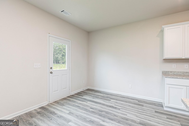 unfurnished dining area with light wood-style flooring, visible vents, and baseboards