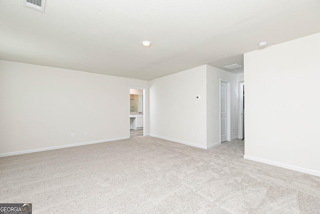 unfurnished room featuring baseboards, visible vents, and light colored carpet