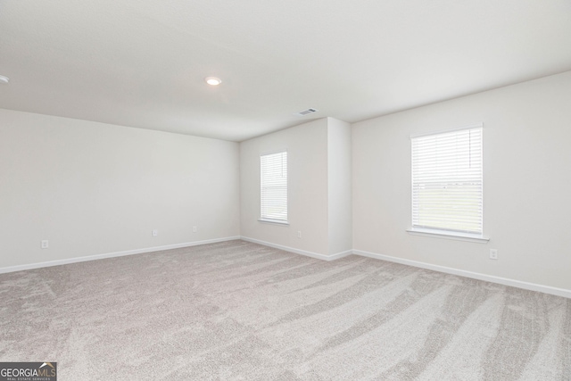 spare room featuring light carpet, baseboards, and visible vents