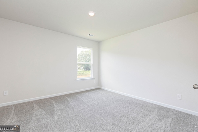 empty room with carpet flooring, visible vents, and baseboards