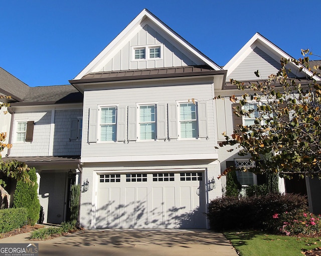 view of front of property featuring concrete driveway, metal roof, an attached garage, a standing seam roof, and board and batten siding