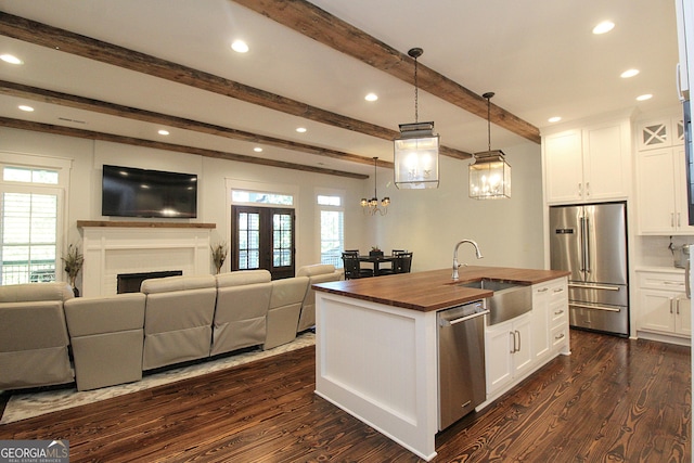 kitchen featuring butcher block counters, stainless steel appliances, a sink, and open floor plan