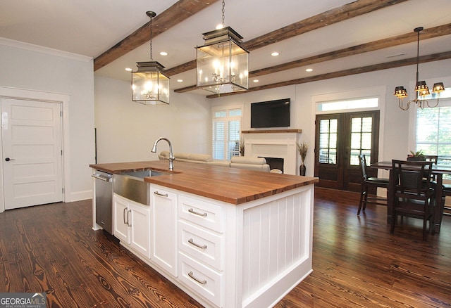 kitchen featuring a kitchen island with sink, dark wood-style flooring, a sink, wood counters, and beamed ceiling