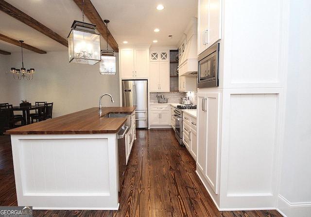 kitchen with wood counters, dark wood-type flooring, beamed ceiling, stainless steel appliances, and backsplash