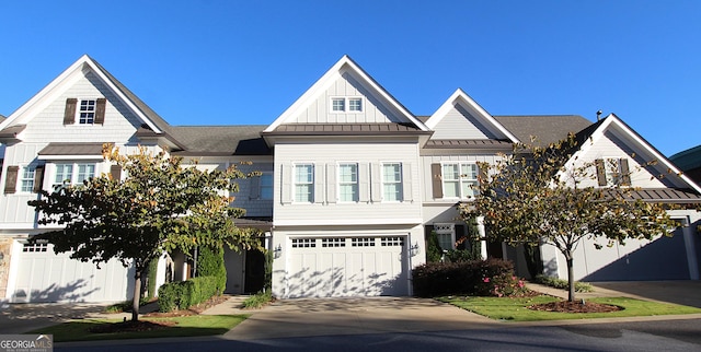 view of front of property with concrete driveway, metal roof, an attached garage, a standing seam roof, and board and batten siding