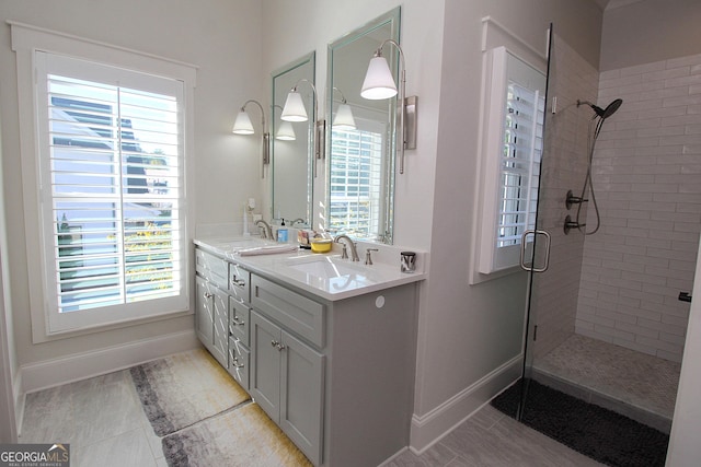 bathroom featuring a stall shower, a sink, baseboards, and double vanity