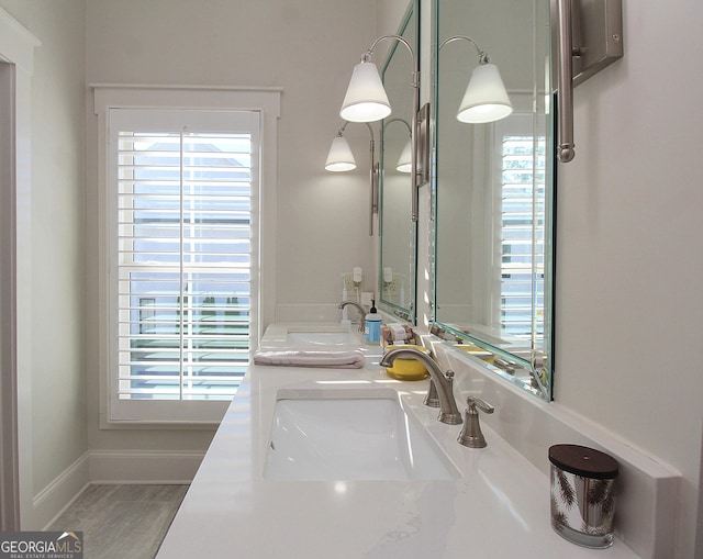 bathroom featuring double vanity, baseboards, and a sink