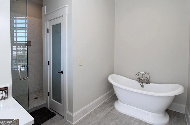 full bath featuring a freestanding bath, a shower stall, and baseboards