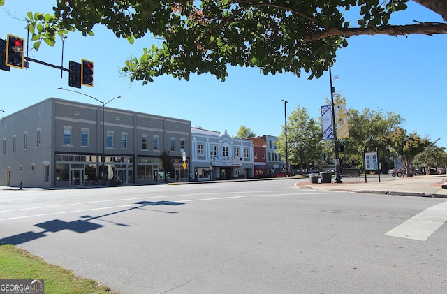 view of street with traffic lights, street lights, traffic signs, sidewalks, and curbs