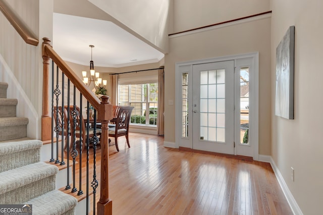 foyer with an inviting chandelier, light wood-style flooring, stairway, and baseboards