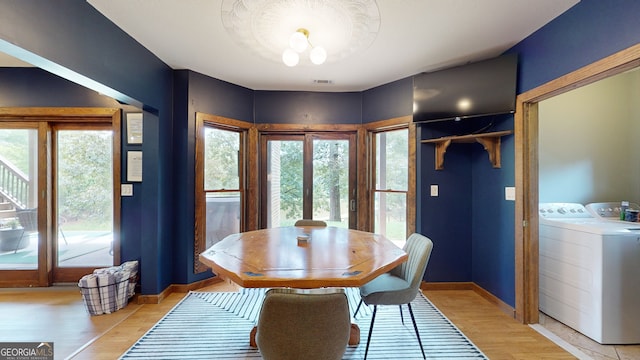 dining area with light wood-style floors, baseboards, visible vents, and separate washer and dryer