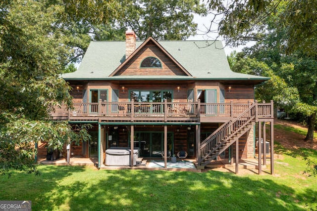 rear view of house with a yard, stairway, a wooden deck, a patio area, and a hot tub