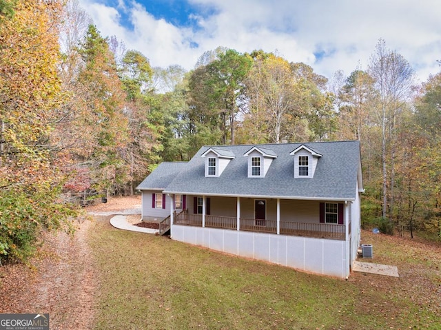 view of front of home featuring central air condition unit, covered porch, roof with shingles, and a front yard