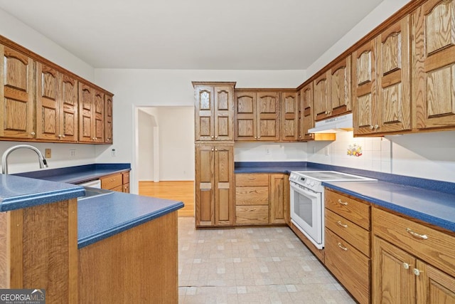 kitchen featuring white range with electric stovetop, brown cabinets, under cabinet range hood, and dark countertops