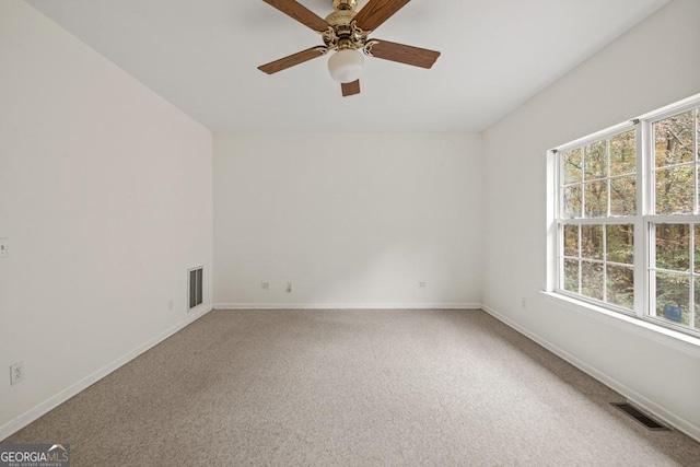 carpeted spare room with visible vents, a ceiling fan, and baseboards