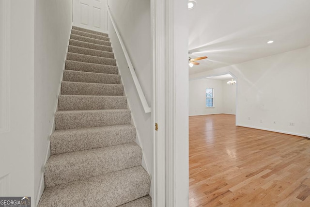 stairs featuring baseboards, recessed lighting, ceiling fan with notable chandelier, and wood finished floors