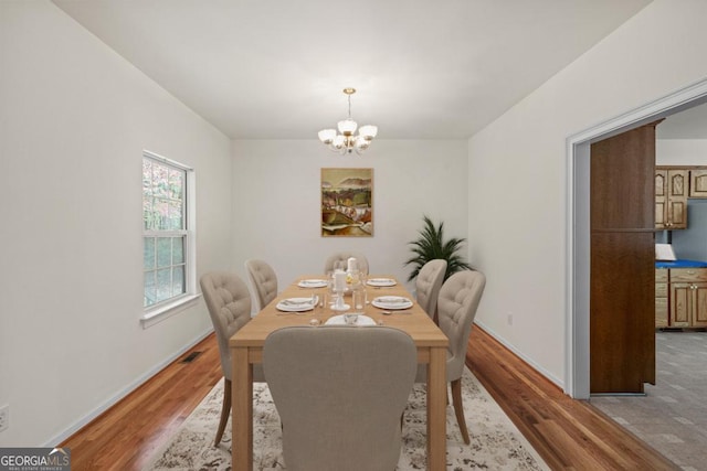 dining space with visible vents, a notable chandelier, light wood-style flooring, and baseboards